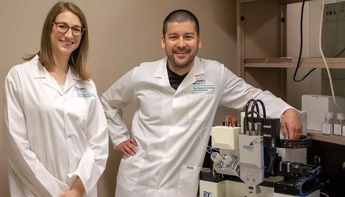 Erin Bedford and Dr. Jeremy Hirota standing next to the Aspect Biosystems RX1™ 3D Bioprinter